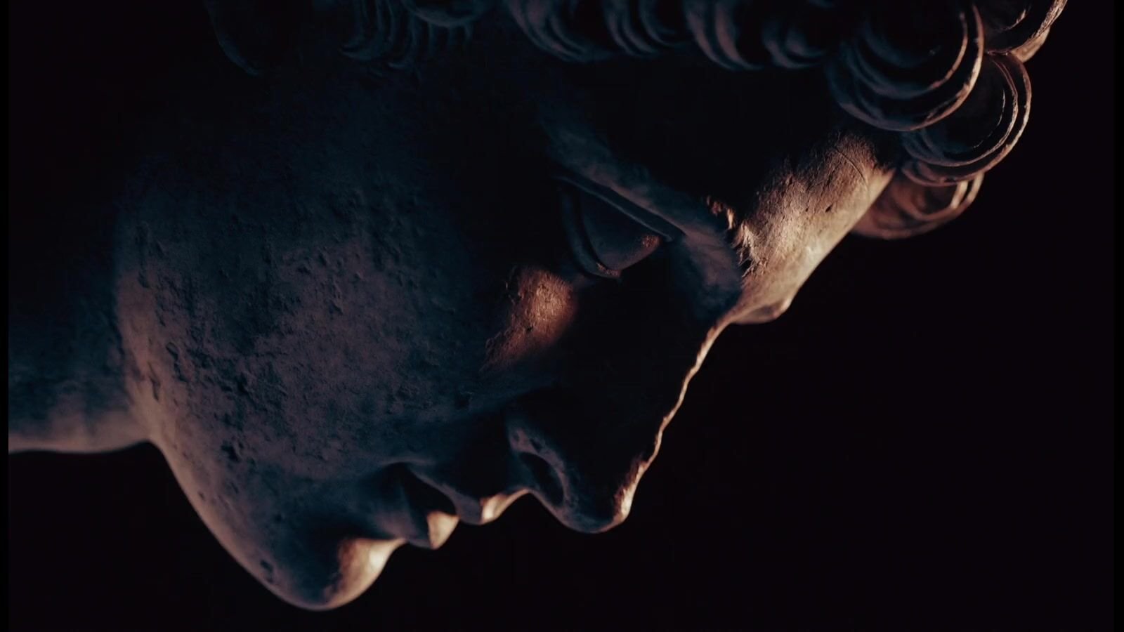 Close-up cinematic portrait of a marble bust lit by a single streak of bronze light, the mark of Polite Rogue